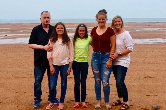 Ian McDonell pose en compagnie de ses trois filles et de sa femme à la plage.