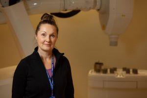Julie Gratton pose devant le système CyberKnife.