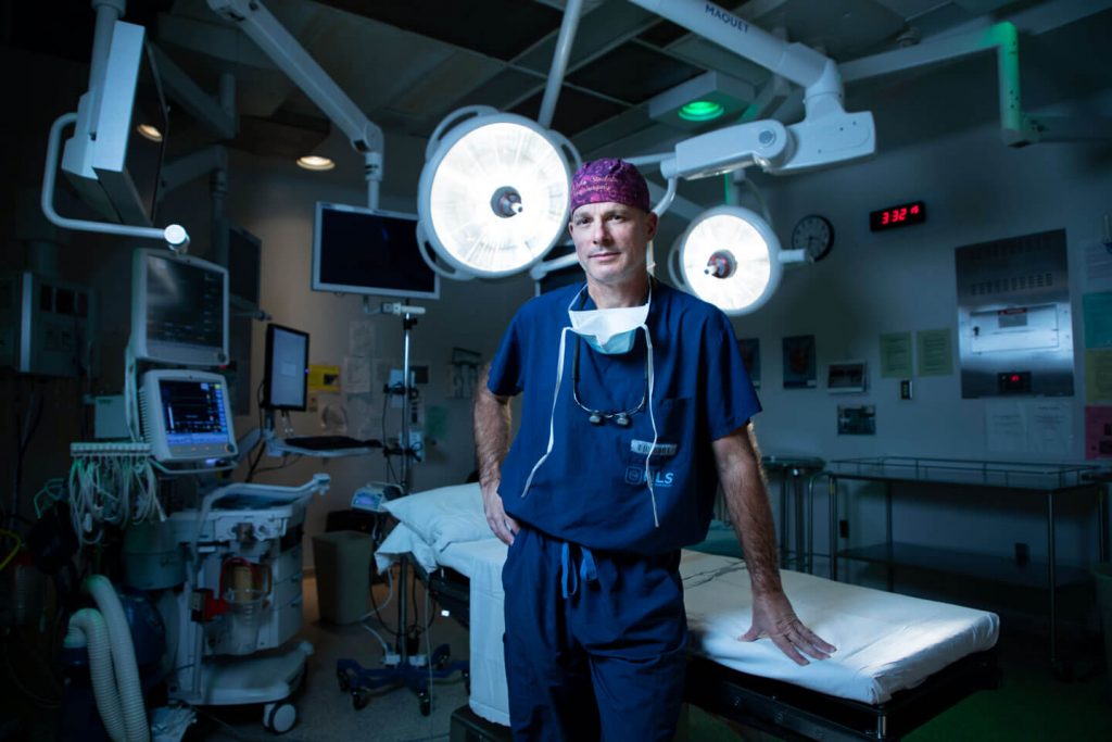 Dr. John Sinclair leaning against bed in the operating room